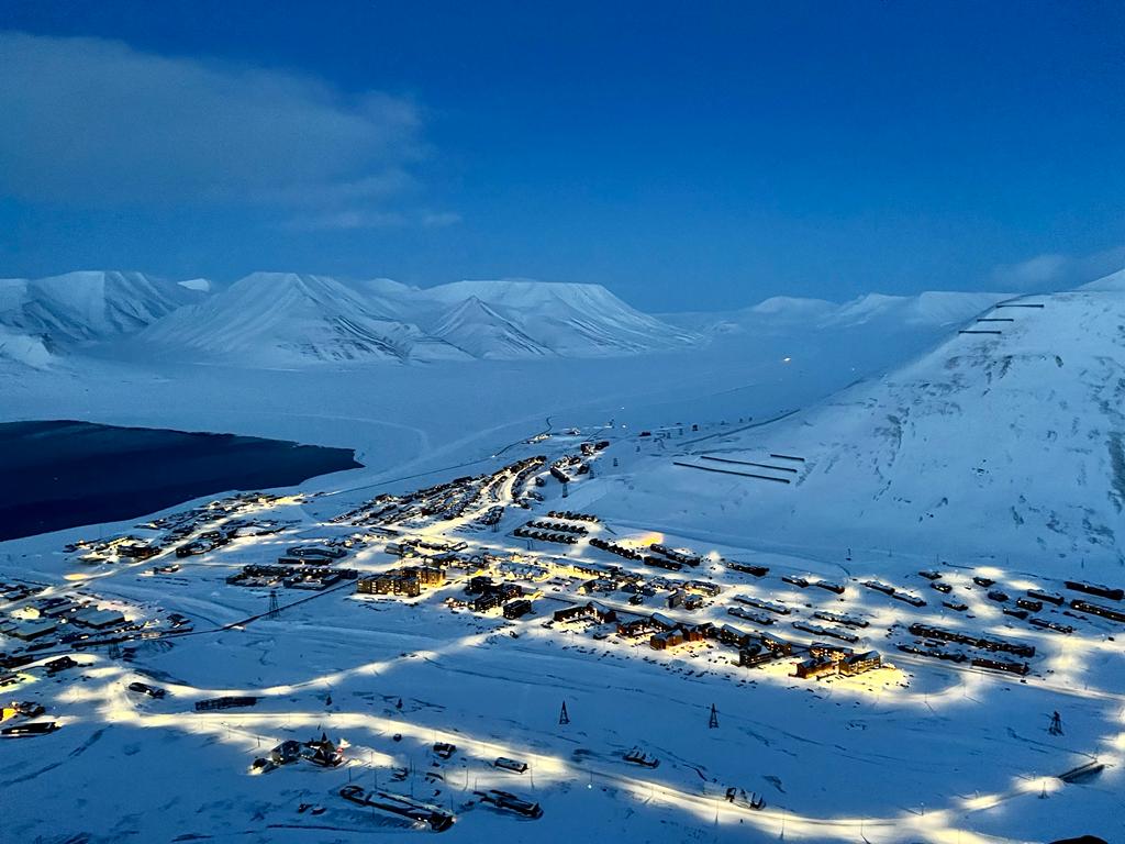 Longyearbyen in the dark seen from an overlooking mountain.